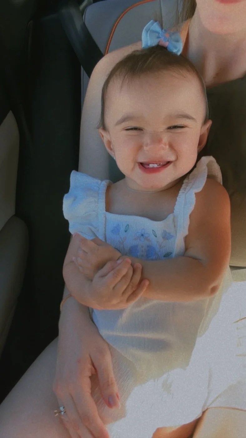 Antonella rindo no colo da mãe, com os dois dentinhos de baixo